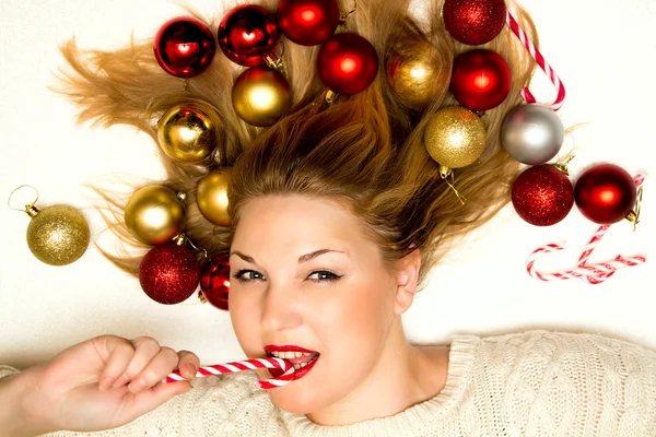 Schöne Blondine mit einem Weihnachtsbonbon auf einem weißen Rücken liegend — Stockfoto