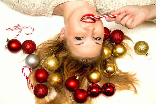 Schöne Blondine mit einem Weihnachtsbonbon auf einem weißen Rücken liegend — Stockfoto