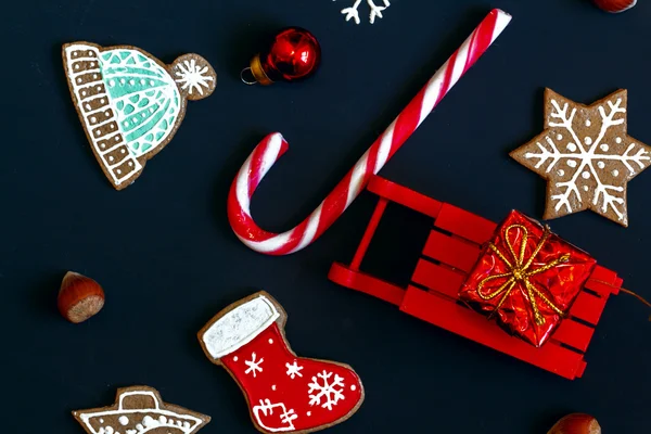 Slitta con regalo, biscotti di Natale, caramelle su sfondo scuro . — Foto Stock