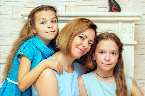 Madre y sus dos hijas sentadas cerca de la chimenea . —  Fotos de Stock