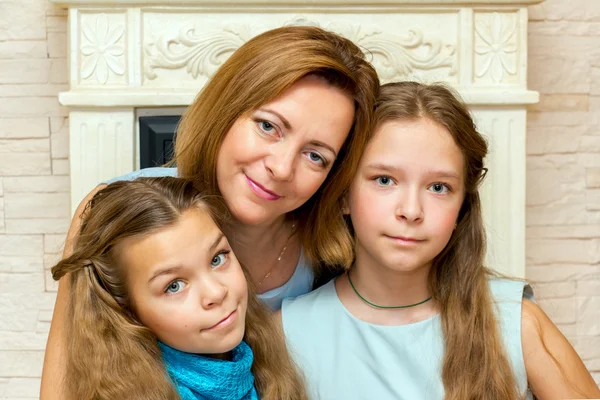 Madre y sus dos hijas sentadas cerca de la chimenea . —  Fotos de Stock