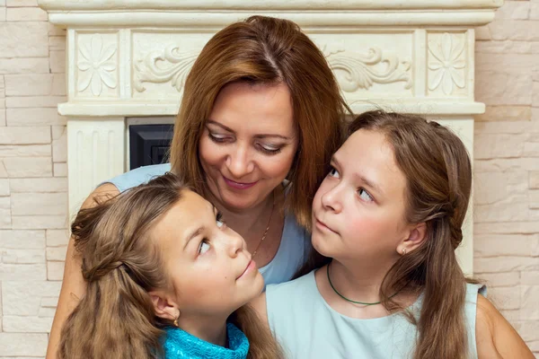 Madre y sus dos hijas sentadas cerca de la chimenea . —  Fotos de Stock