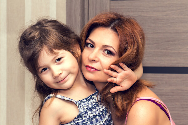 Beautiful little girl hugging her mother.