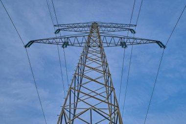 Mavi gökyüzünün önündeki elektrik direğinin alçak açılı görüntüsü. Mavi gökyüzündeki bir iletim kulesinin alçak açılı görüntüsü.