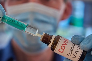 Yüz maskeli araştırmacı şırıngayı ilaçla dolduruyor. Şırıngada Covid-19 aşısı. Covid 19 aşısı. Coronavirus aşısı. Coronavirus ilacı. Biontech aşısı. Hemşire elinde şırınga tutuyor. Doktor elinde şırınga tutuyor. İlaç şişesi.