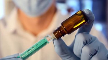 Yüz maskeli araştırmacı şırıngayı aşıyla dolduruyor. Covid-19 aşısı. Corona aşısı. Biontech aşısı. Biontech koronası. Covid-19 ilaçları. Coronavirus ilacı. İlaç şişesi.