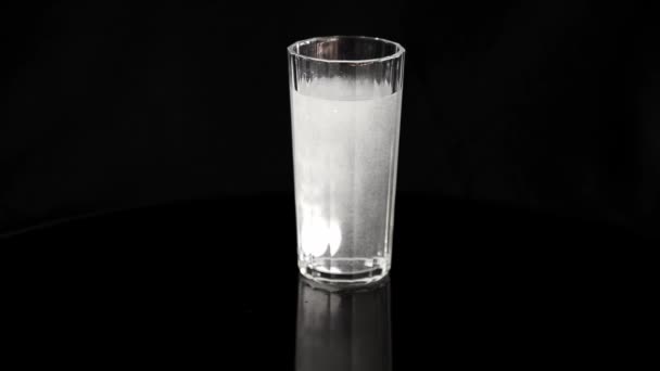 Egy pezsgőtabletta feloldása egy pohár vízben. Egy pezsgőtabletta leejtése egy pohár vízbe.