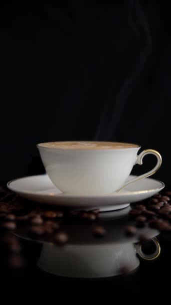 把热气腾腾的咖啡放在黑色的表面上 黑表面上的卡布奇诺和咖啡豆杯 — 图库视频影像