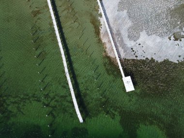 Kısmen donmuş bir dağ gölündeki ahşap rıhtım manzarası. Kısmen donmuş bir gölün kuş bakışı görüntüsü.