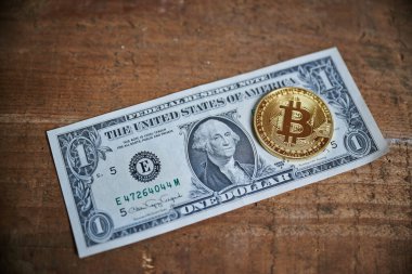 Altın Bitcoin madalyasının bir dolarlık banknota yakın çekimi..