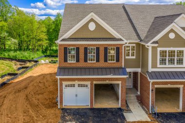 İşçiler Maryland 'de golf sahasının ortasında çift garajlı, mavi gökyüzü bulutlu gayrimenkul gelişimine son rötuşu yapmadan önce geniş bir alana sahip Triplex kasaba kompleksi.