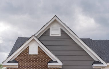 Ters çift gable, lüks, tek kişilik aile evine yakın çekim. Kare tek cam gable penceresi. Geleneksel evin çatı çizgisi, bir gable bir yönde çalışan ters gable diğer yönde çalışan.