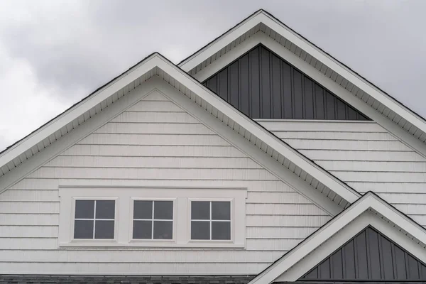 美国东海岸一幢新建造的单身家庭住宅上 有三层有厚实白色框架 三层阁楼窗户 白色水平乙烯侧边 深色垂直侧边的三格墙 — 图库照片