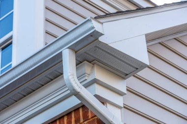 Close up of white frame gutter guard system, eaves through, fascia, drip edge, colonial white soffit with ventilation, brick facade siding on a luxury American single family home neighborhood USA clipart