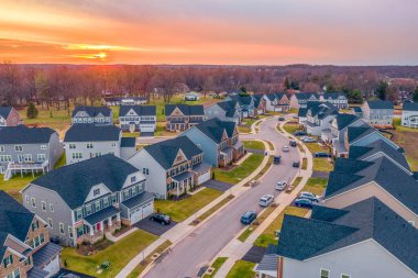 Maryland 'de, turuncu günbatımı gökyüzü olan tek kişilik lüks bir aile evinin kavisli mahalle manzarası.