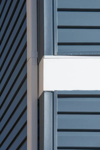 Colonial white gutter guard system,  soffit providing ventilation to the attic, with gray vinyl horizontal siding at a luxury American single family home neighborhood USA