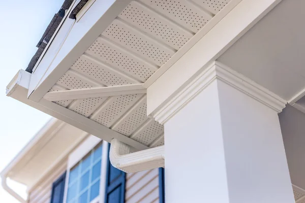 Colonial white gutter guard system,  soffit providing ventilation to the attic, with pacific blue vinyl horizontal siding at a luxury American single family home neighborhood USA