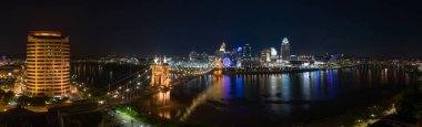 Cincinnati 'nin panoramik gece manzarası Ohio nehri üzerindeki tarihi Roebling asma köprüsü