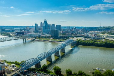 The yellow Daniel Carter Beard Bridge and the Purple People Bridge in Cincinnati Ohio over the Ohio river with blue sky clipart