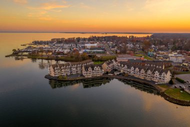 Maryland 'deki Havre de Grace şehir merkezinin havadan görünüşü. Güneş gökyüzünü turuncuya boyarken deniz kenarındaki lüks apartman kompleksi suya yansıyor.