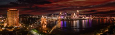 Cincinnati 'nin panoramik gece manzarası Ohio nehri üzerindeki tarihi Roebling asma köprüsü