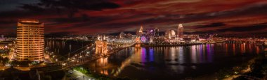 Panoramic night view of Cincinnati downtown with the historic Roebling suspension bridge over the Ohio river clipart
