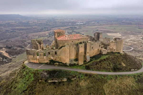 Aerial view of the ruined medieval abandoned Montearagon castle, namesake of the famous kingdom on a bare mountain top near Huesca, Aragon province Spain with blue sky