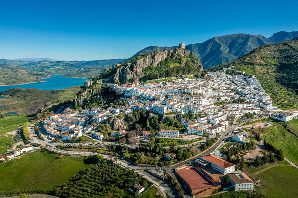 Aerial view of Zahara de la Sierra one of the white towns or Pueblos Blancos, in Andalucia Spain, with a ruined medieval castle and the man made lake formed by the Guadalete river high damn