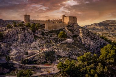 İspanya 'nın Valencia eyaletindeki Castalla Kalesi' nin havadan görünüşü kasabanın üzerinde donjon kulesi ve güneşin üzerinde dairesel bir kuleyle güçlendirilmiş bir avlu.