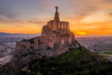 Monteagudo Ortaçağ Şatosu tepeyi çevreleyen on iki dikdörtgen kuleyi ve Murcia İspanya yakınlarındaki İsa Mesih heykelinin kutsal kalbini harabeye çevirdi.