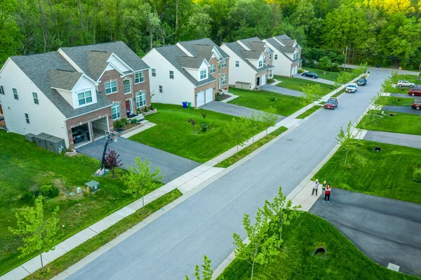 American luxury real estate single family houses with brick facade and two car garages in a new construction Maryland street neighborhood USA aerial