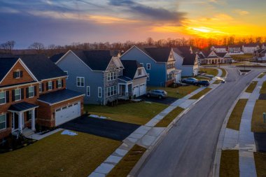 Çok katlı tek katlı bir evin havadan görünüşü Maryland USA 'de yeni bir yerleşim yeri olan banliyö mahallesinde, dramatik renkli günbatımı gökyüzü ile tek aile evleri.
