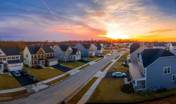 Çok katlı tek katlı bir evin havadan görünüşü Maryland USA 'de yeni bir yerleşim yeri olan banliyö mahallesinde, dramatik renkli günbatımı gökyüzü ile tek aile evleri.