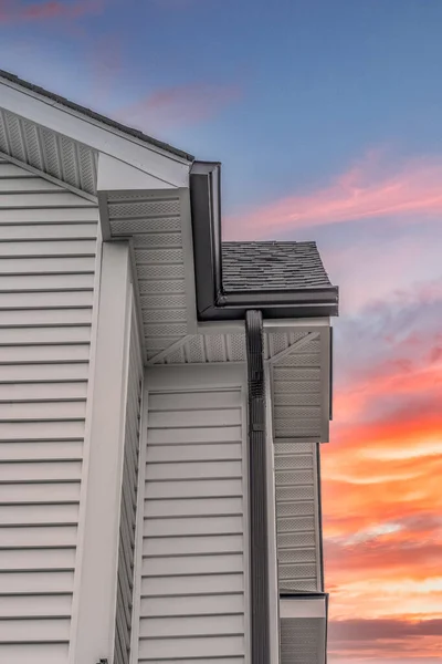在一个豪华的美国单身家庭的屋顶阁楼上的白色水平乙烯边框 软泥上的深色金属排水沟系统的闭合视图 戏剧性的日落天空背景 — 图库照片