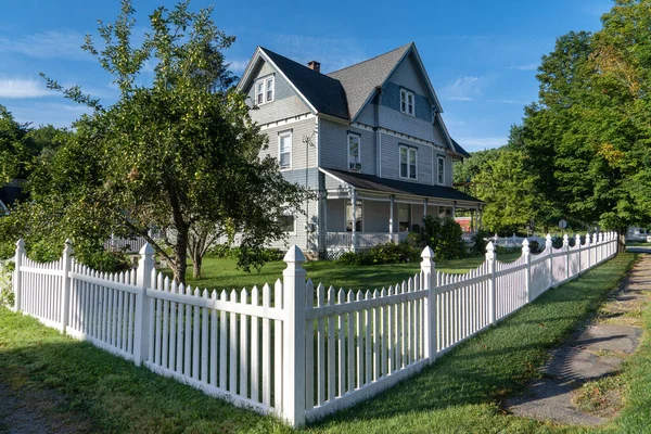 Blue Victorian mansion, inn in rural Pennsylvania, neatly restored with white picket fence blue sky