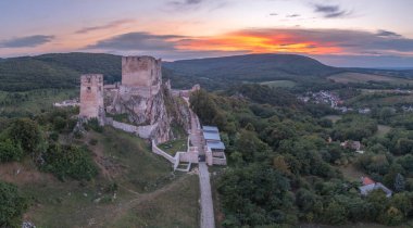 Macaristan 'ın Veszprem ilçesindeki Bakony bölgesindeki harap Gotik Şatosu' nun hava manzarası. Eski saray binası, renkli dramatik gün batımına sahip kapı kulesi.