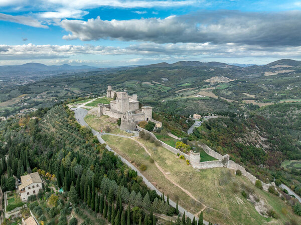 An aerial view of Assisis Rocca Maggiore fortress crowning the hill above terracotta roofs and Umbria