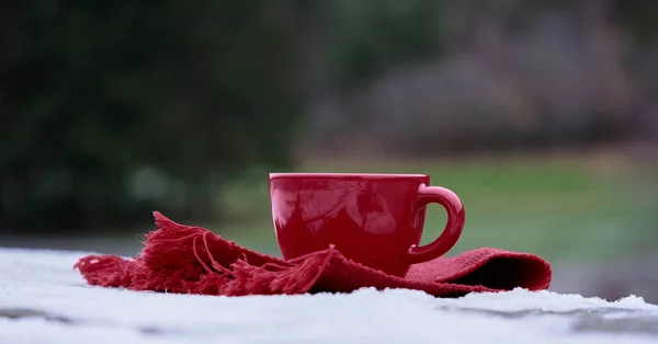 Red mug on snow table on red towel with blurred background Royalty Free Stock Images