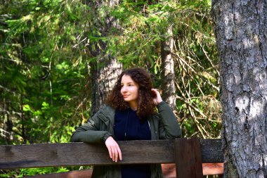 Genç kıvırcık kız, kırmızı ceket, yürüyüş ormanı, koru, sonbahar güneşi