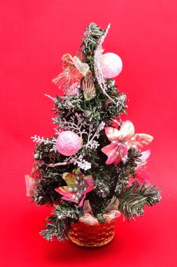 Noel oyuncakları, yapay Noel ağacı, dalların üzerinde oyuncaklar ve hediyeler, kırmızı arka planda