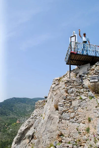 Aktivní starší turista stojící na vrcholku kopce a mávající pro úspěch rukou. Aktivní dospělá osoba. Zdravý životní styl. Vrchol hradu Saint Hilarion v oblasti Kyrenie Severní Kypr. — Stock fotografie