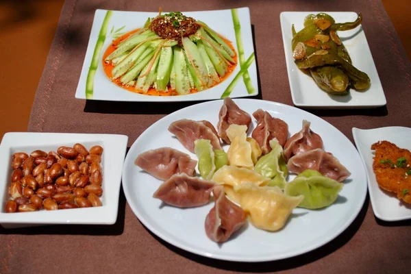 Masada çeşitli yan yemekleri olan renkli ev yapımı hamur tatlısı. Jiaozi.. 
