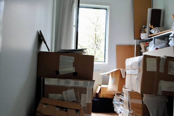 Paketleme konsepti. Penceresi açık küçük bir odada dağınık karton kutular.. 