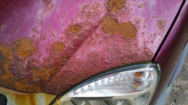 Metal corrosion of old car. Rusty surface, background and damaged texture from road salt. Automobile headlight. Remove steel rust from vehicle. Protection and painting auto concept. Professional paint