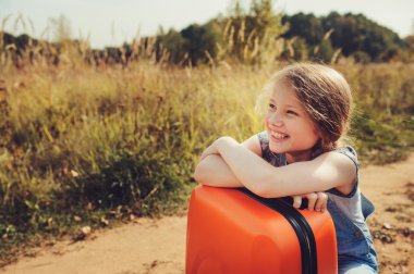 yaz tatilinde seyahat turuncu bavul ile mutlu çocuk kız. Çocuk taşraya gidiyor. Rahat kırsal sahne