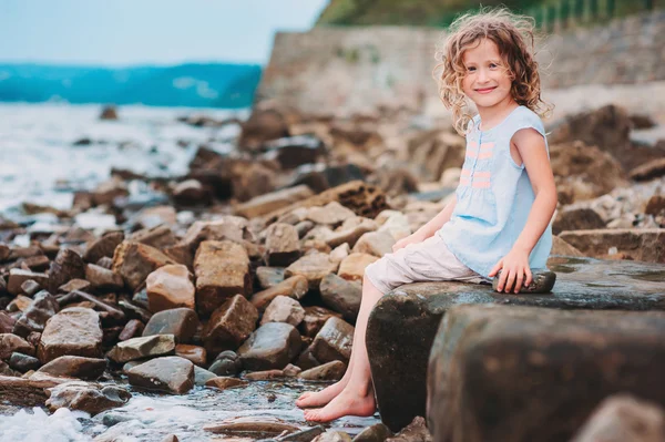 Niña feliz jugando con agua en la playa de piedra. Acogedoras vacaciones en el mar, viajando con niños . — Foto de Stock