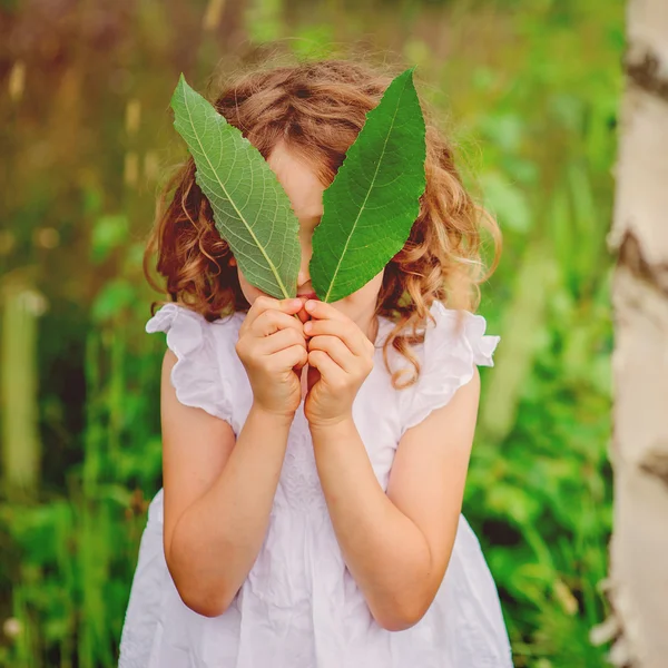 Dítě dívka si hraje s listy v létě lesa. Vodní aktivity s dětmi. Venkovní aktivity venkova. — Stock fotografie
