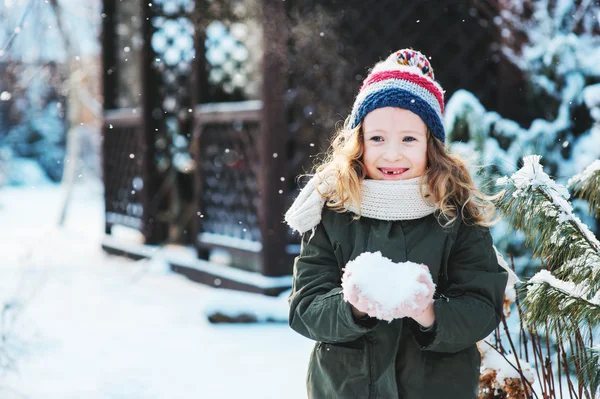 Szczęśliwe dziecko dziewczynka bawi się śniegu na snowy zimowy spacer na podwórku, Dokonywanie śnieżkami w ogrodzie — Zdjęcie stockowe