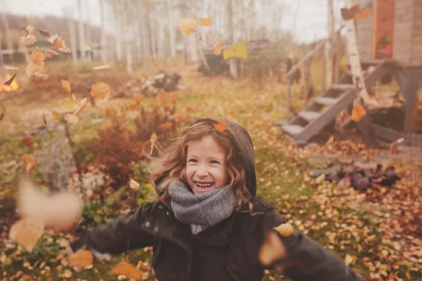 Glückliches Kind, das im Herbst mit Blättern spielt — Stockfoto