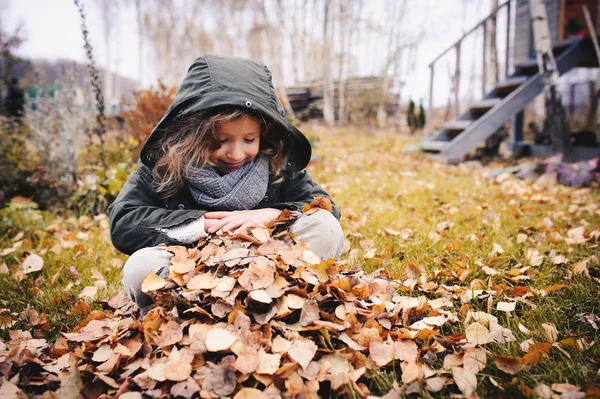 Criança feliz brincando com folhas no outono — Fotografia de Stock